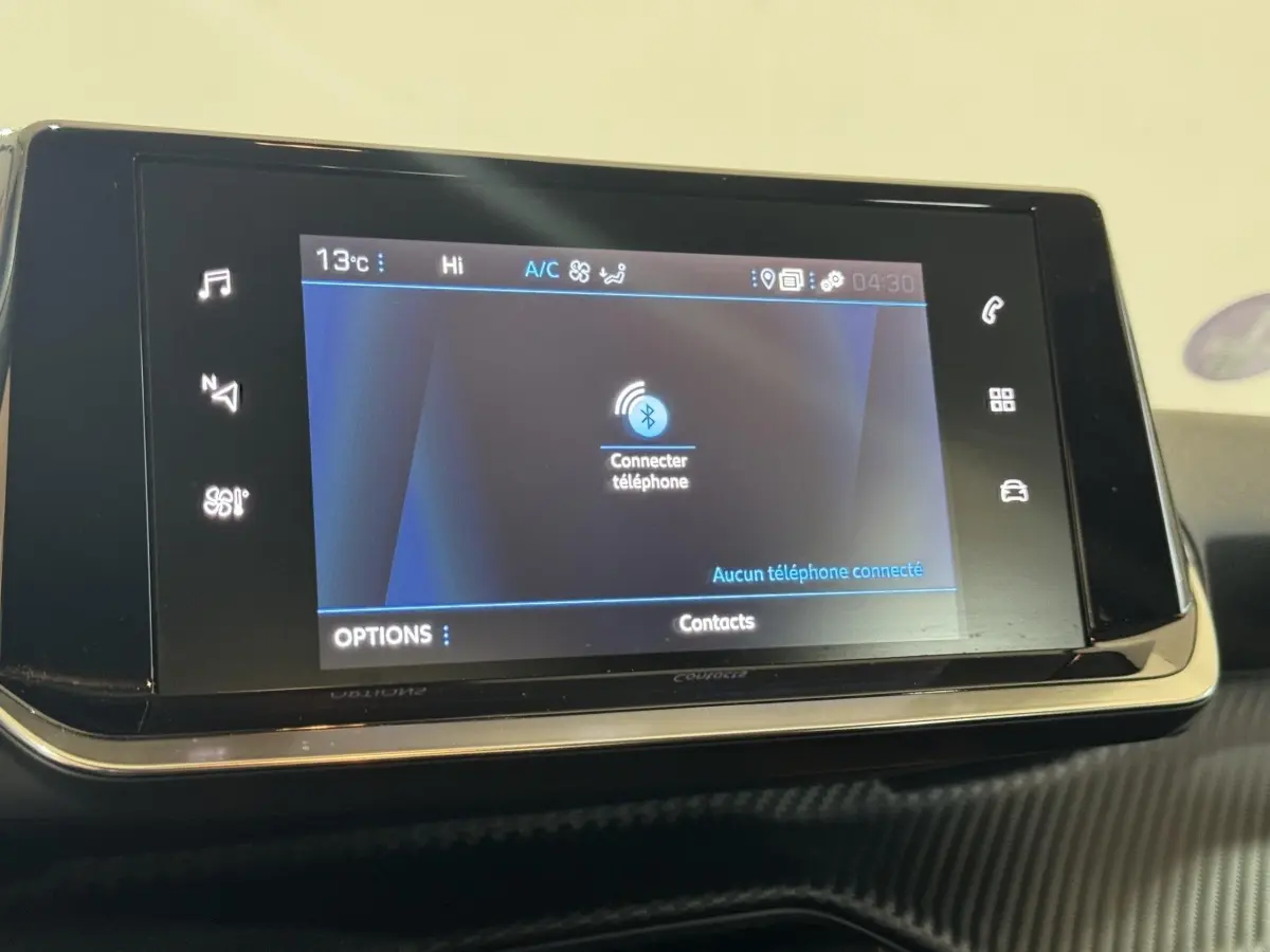 Écran tactile central du tableau de bord du Peugeot 2008 noir, affichant la connexion Bluetooth au téléphone.