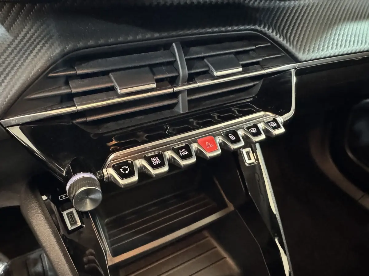 Gros plan sur la console centrale noire du Peugeot 2008 avec boutons de commande et prise USB visible.
