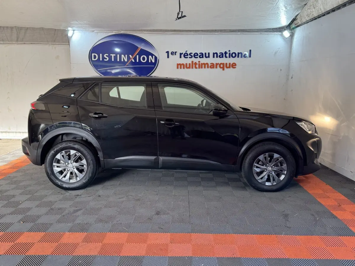 Profil côté gauche d'un Peugeot 2008 noir 2022 PureTech 130 S&S ACTIVE PACK dans un showroom intérieur.