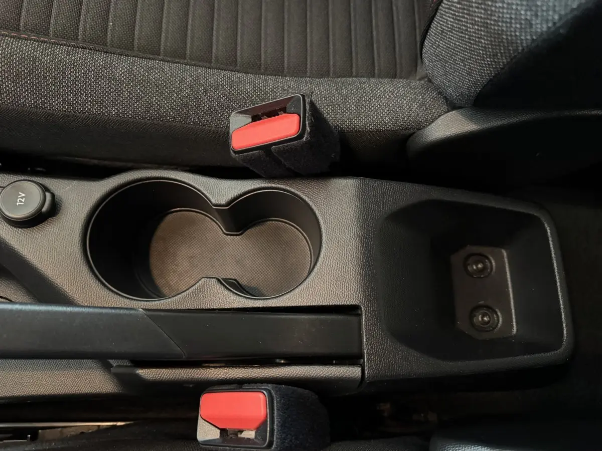 Vue rapprochée de la console centrale noire avec porte-gobelets et frein à main, sièges tissu gris foncé Peugeot 2008.