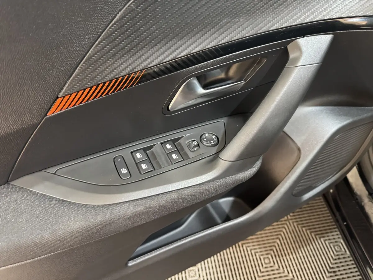 Gros plan sur la porte avant gauche noire du Peugeot 2008 2022, avec commandes des vitres et poignée intégrée.