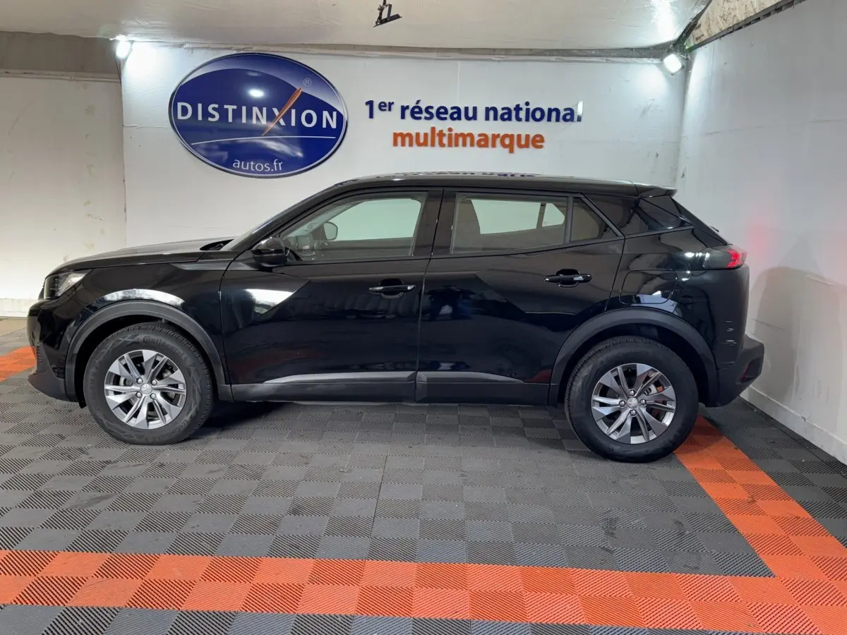 Profil côté gauche d'un Peugeot 2008 noir 2022 garé en intérieur, avec jantes alliage et rétroviseurs ton caisse.