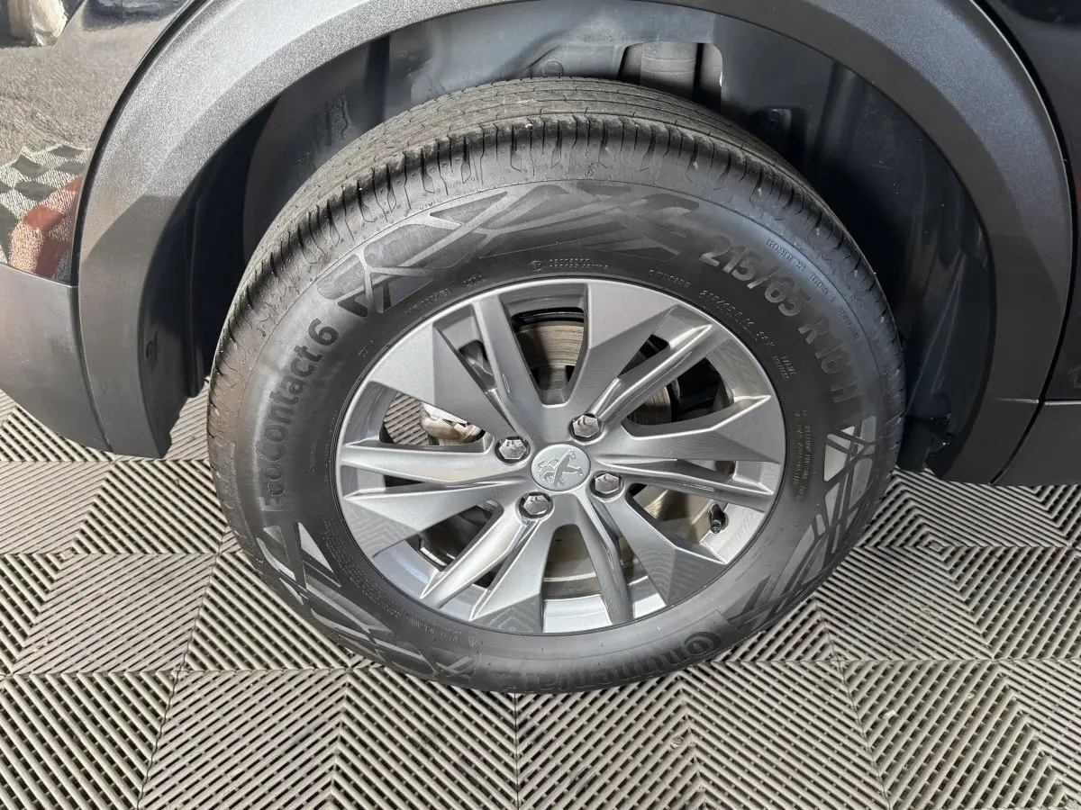 Gros plan sur la roue avant droite de la Peugeot 2008 noire, mettant en valeur la jante alliage et le pneu Continental.