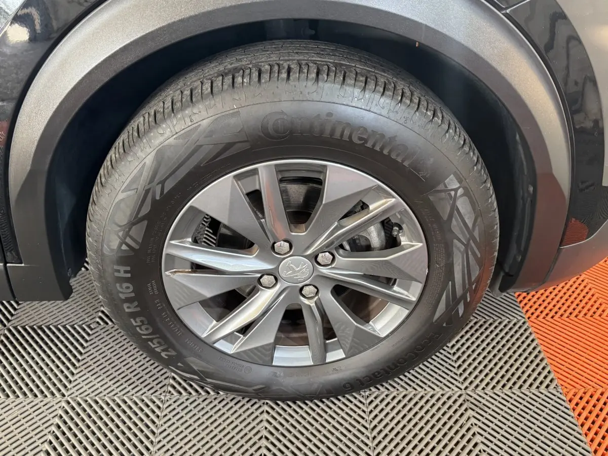 Gros plan sur la roue avant gauche noire du Peugeot 2008 PureTech 130 S&S ACTIVE PACK avec jante alliage grise.