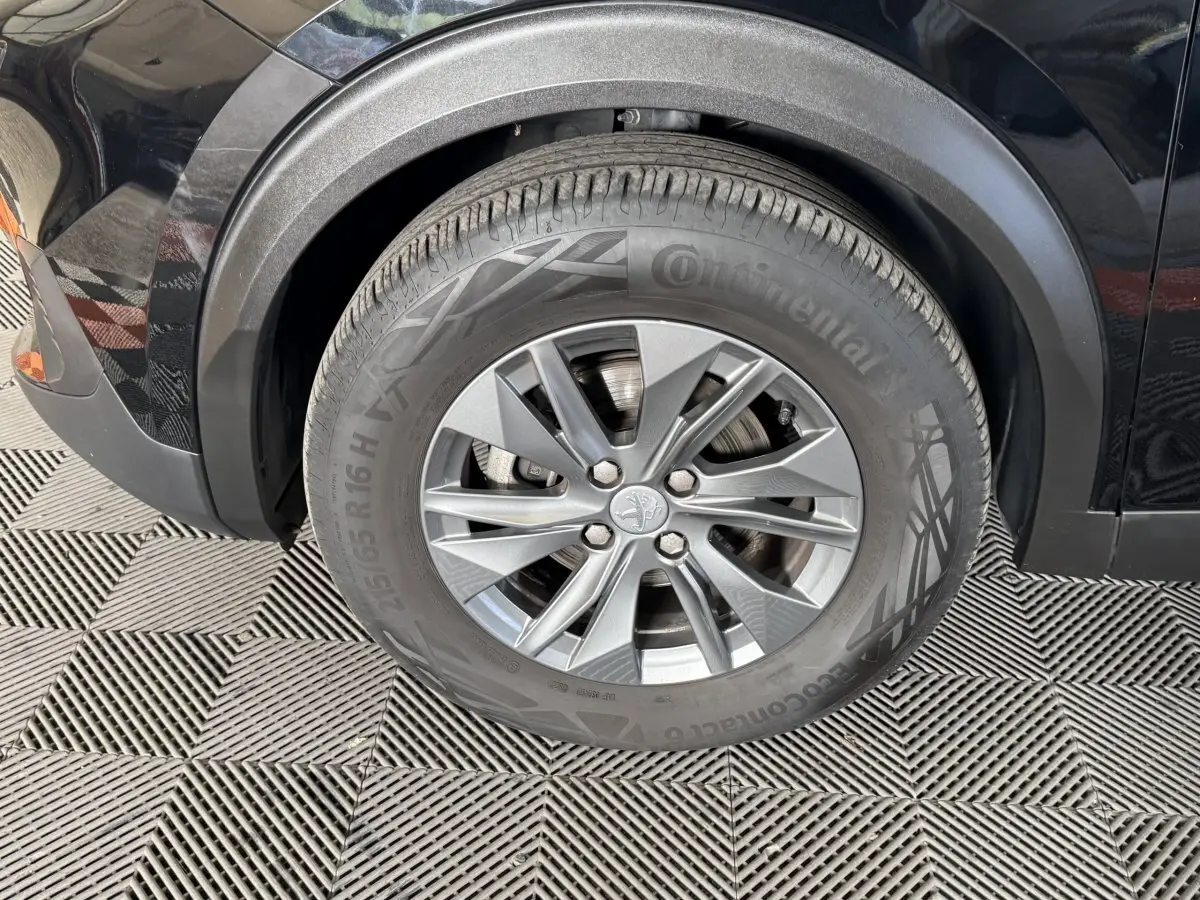 Gros plan sur la roue avant gauche d’un Peugeot 2008 noir, avec passage de roue en plastique noir mat.