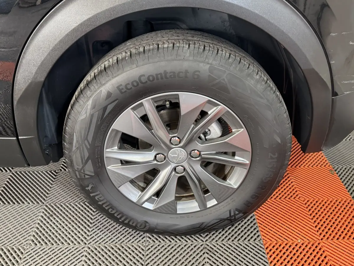 Gros plan sur la roue avant droite d’un Peugeot 2008 noir, mettant en valeur la jante alliage et le pneu Continental EcoContact 6.