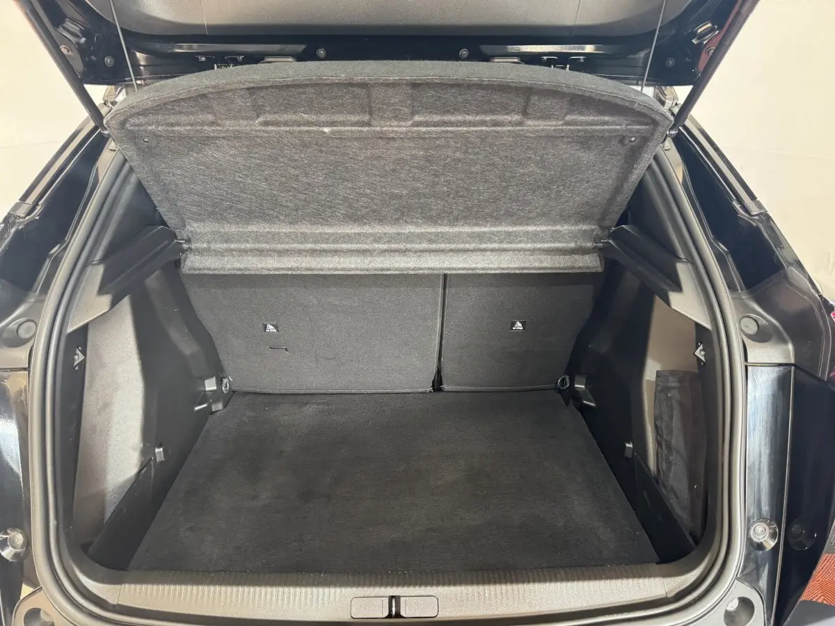 Coffre ouvert vu de l'arrière d'une Peugeot 2008 noire, montrant un espace de chargement propre et spacieux.