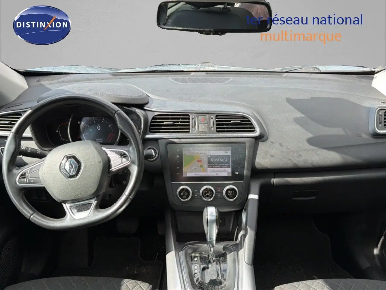 Vue intérieure du tableau de bord du Renault Kadjar gris Highland, montrant le volant, l'écran tactile et la console centrale.