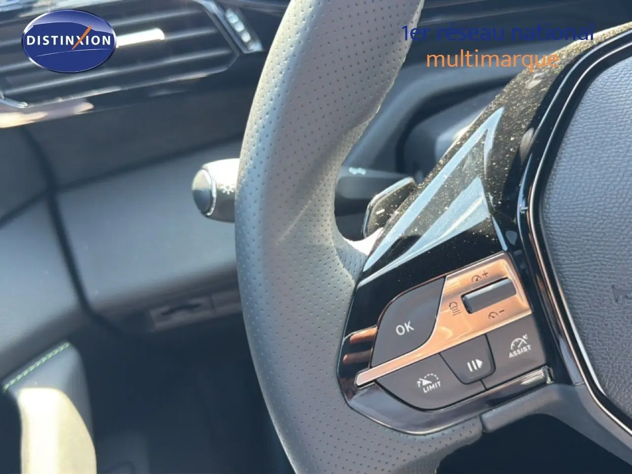 Gros plan sur le volant perforé gris avec commandes intégrées du Peugeot 308 Hybrid 145ch GT noir perle métal.