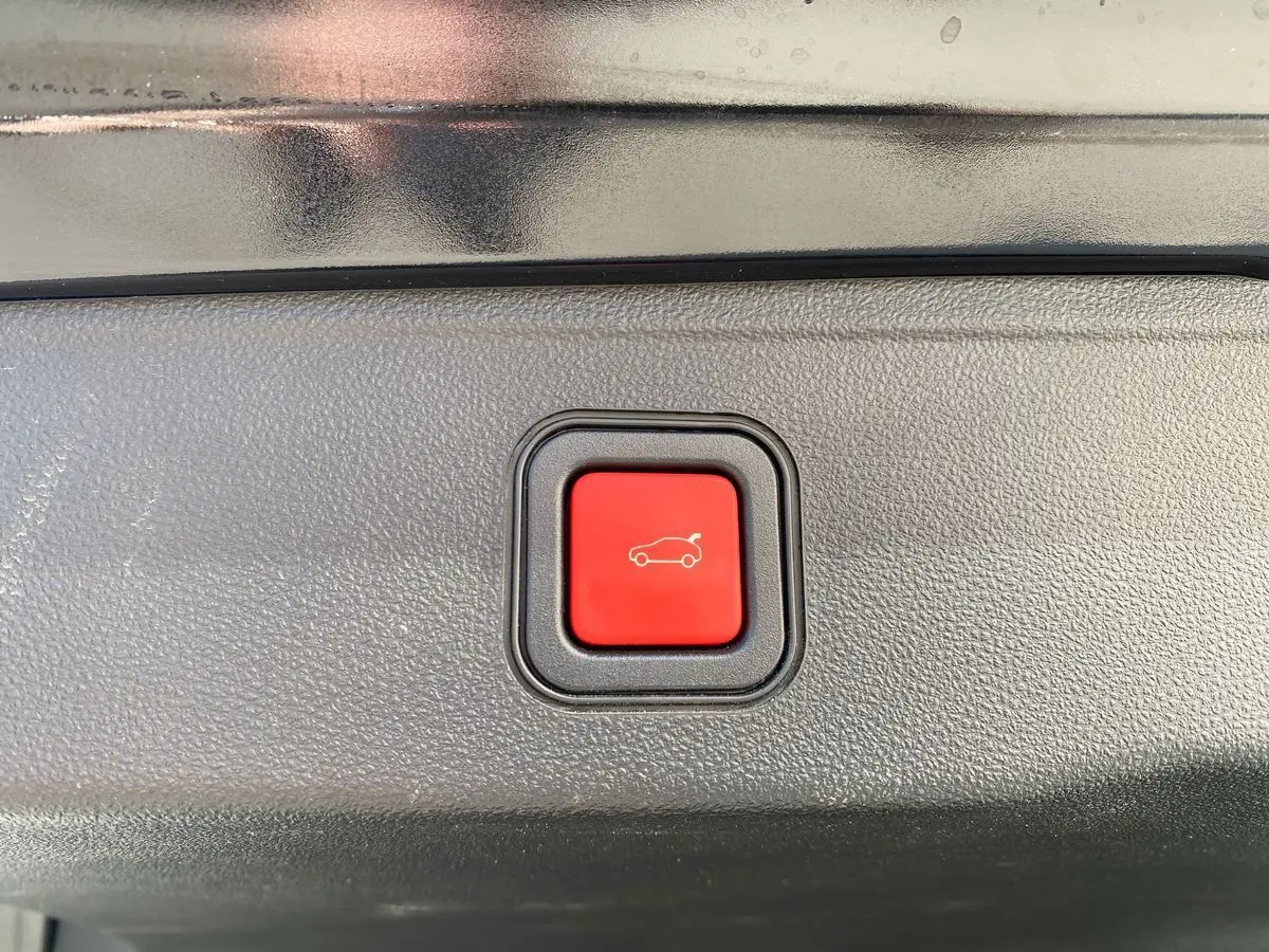 Bouton rouge d'ouverture électrique du coffre sur un Jeep Avenger noir électrique 2023, vue rapprochée intérieure.