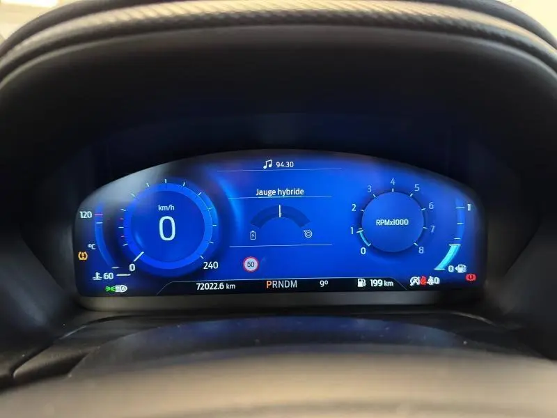 Vue rapprochée du tableau de bord numérique bleu du Ford Puma 2022 affichant vitesse, compte-tours et jauge hybride.