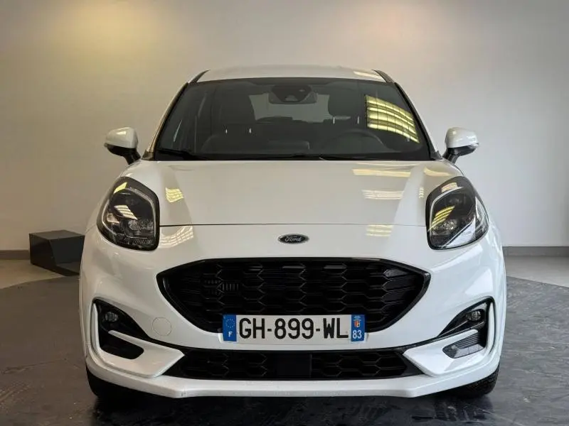 Vue frontale d'une Ford Puma blanc glacier avec calandre noire et phares avant distinctifs en intérieur neutre.