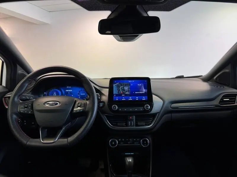 Tableau de bord et volant multifonction du Ford Puma blanc, avec écran tactile central affichant la navigation.