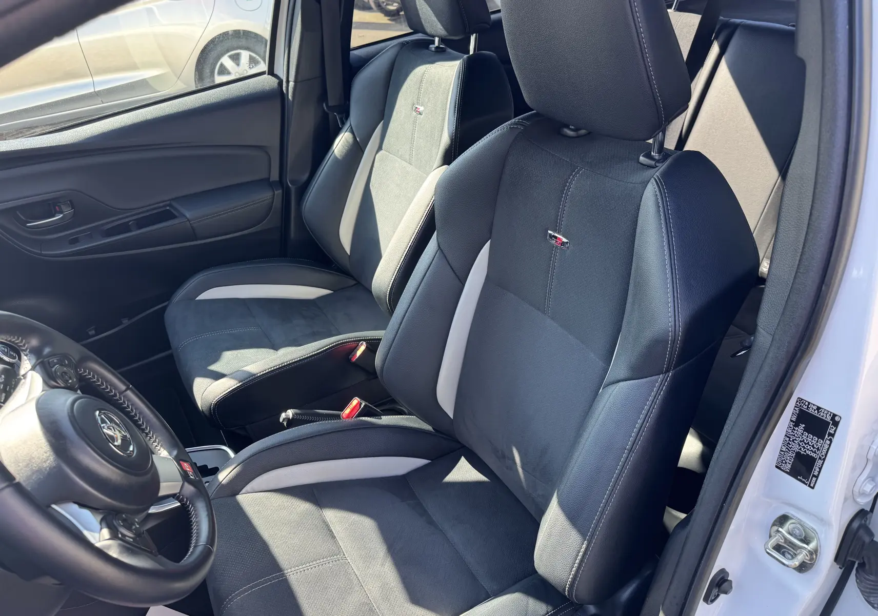 Vue intérieure côté conducteur de la Toyota Yaris Hybride GR Sport 2020 avec sièges noirs et inserts gris clairs.