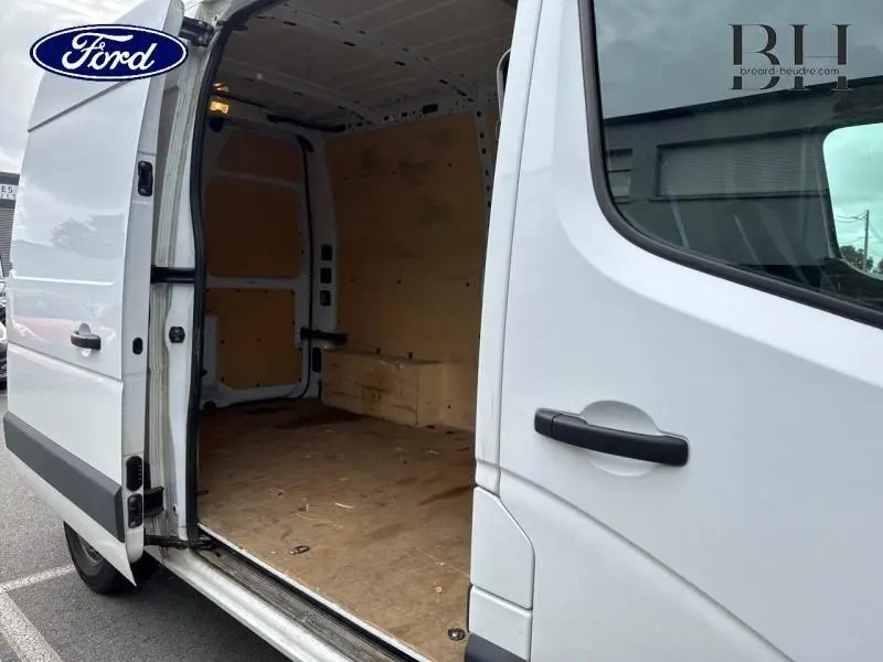 Vue latérale droite d'un Renault Master blanc minéral avec porte coulissante ouverte montrant l'espace de chargement vide en bois.