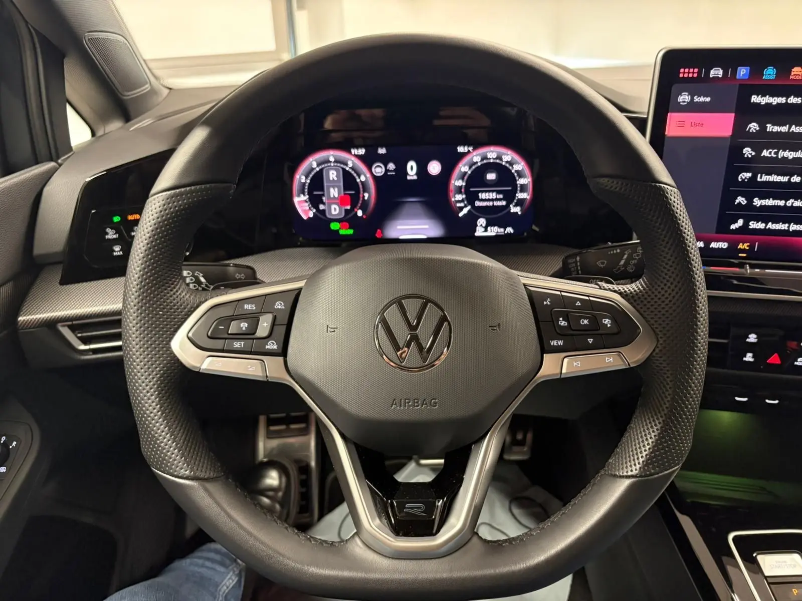 Vue rapprochée du volant multifonction noir de la Volkswagen Golf 1.5 eTSI 150 DSG7 R-Line Edition avec tableau de bord numérique.