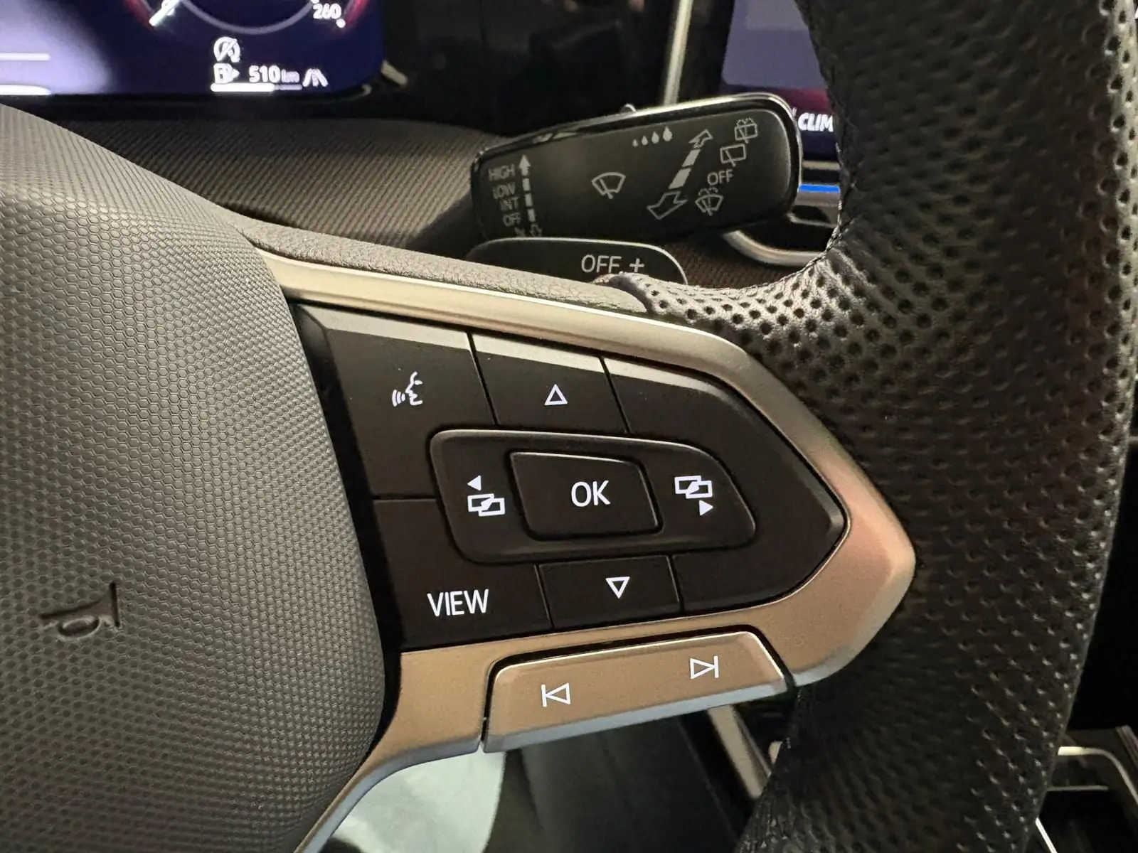 Gros plan sur les commandes multifonctions à droite du volant perforé d’une Volkswagen Golf Gris Dauphin 2025.