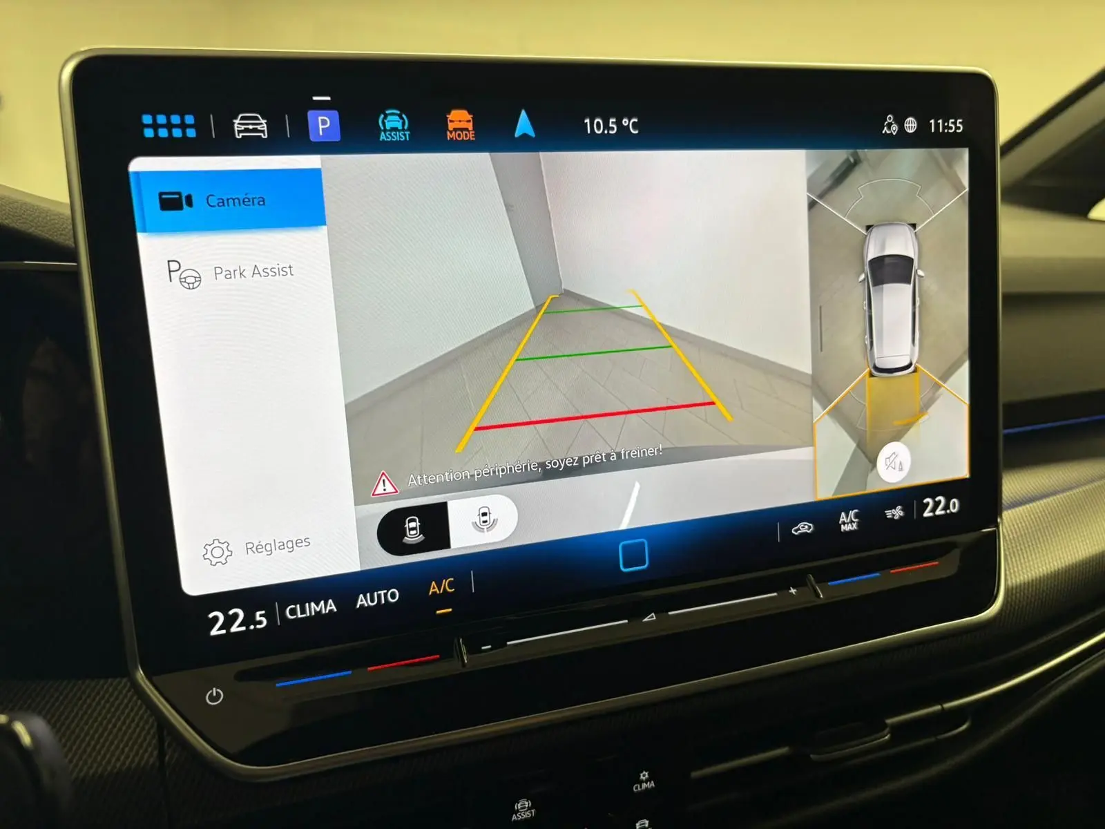 Écran tactile intérieur de la Volkswagen Golf 2025 affichant la caméra 360° en vue arrière avec lignes de guidage colorées.