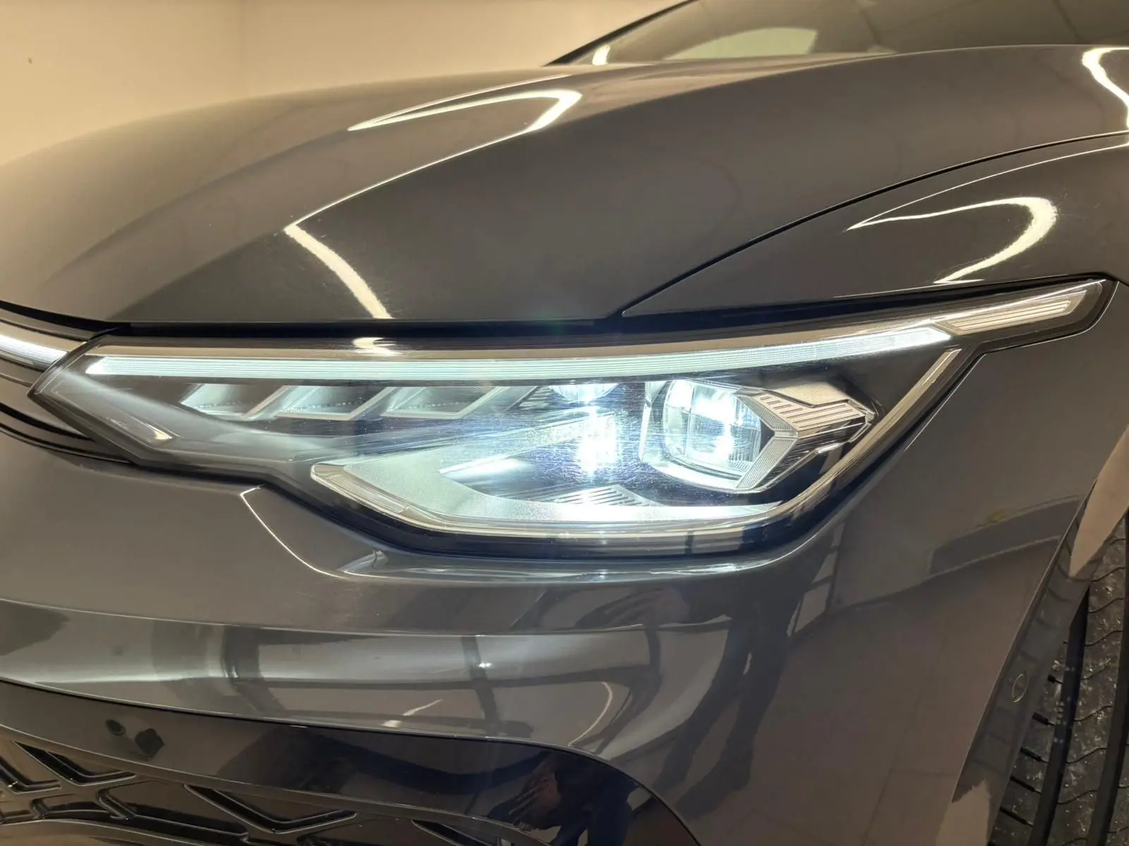 Gros plan sur le phare avant droit d’une Volkswagen Golf 1.5 eTSI Gris Dauphin avec éclairage LED distinctif.