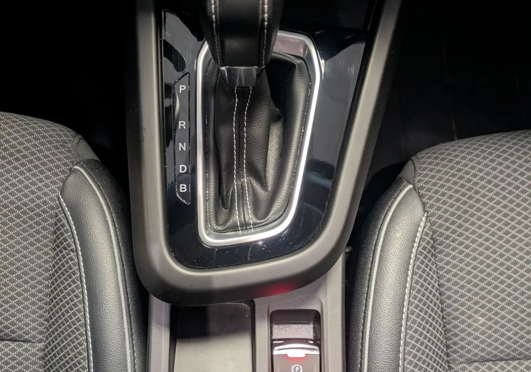 Vue plongeante sur la console centrale du Renault Arkana noir 2023, avec levier de vitesse automatique et sièges tissu gris.