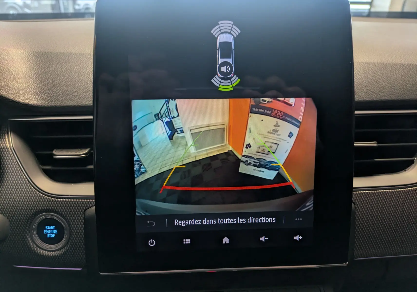 Écran central de la Renault Arkana noir 2023 montrant la caméra de recul avec guidage coloré et alertes de proximité.