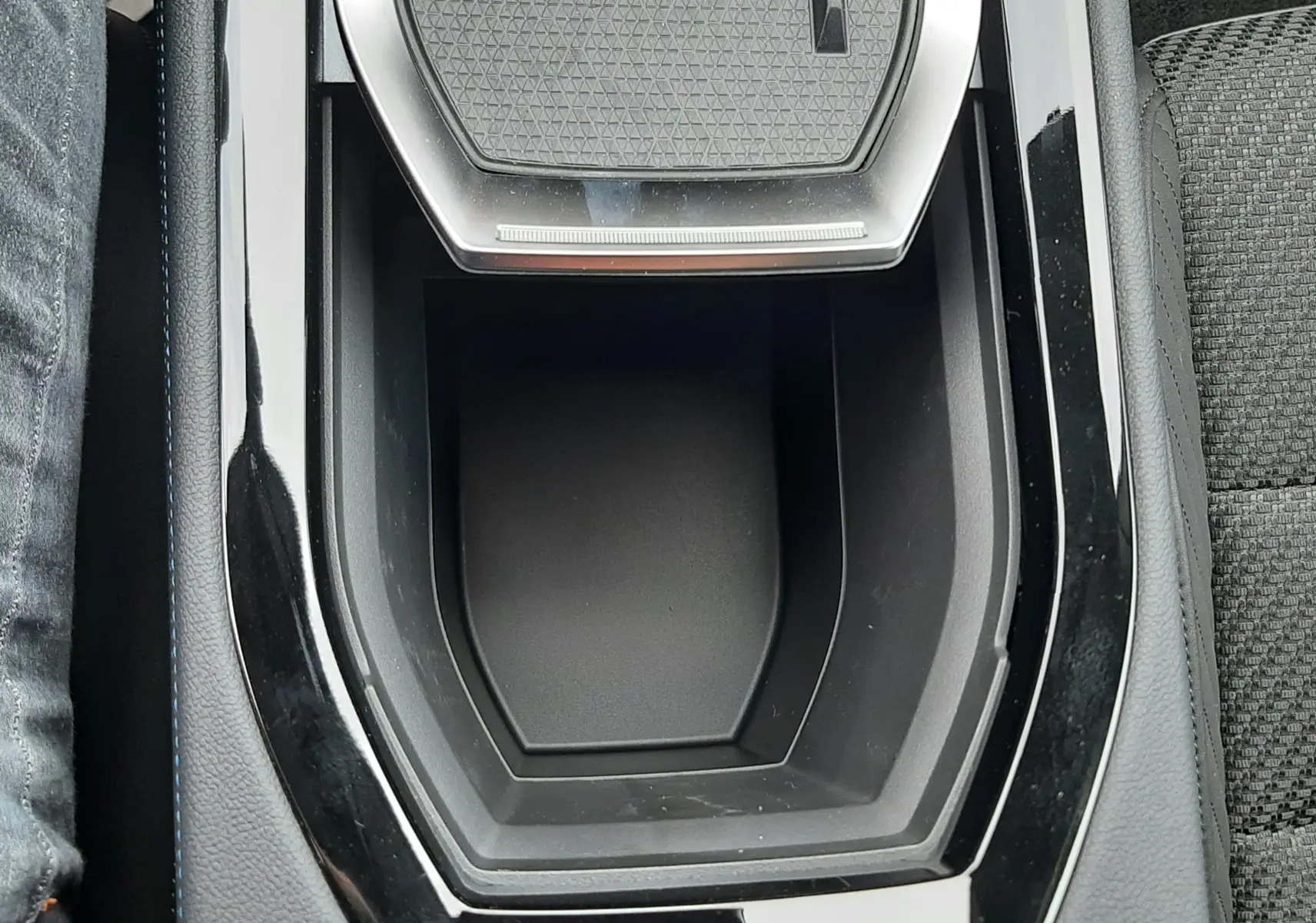 Vue rapprochée de la console centrale noire brillante avec zone de recharge sans fil du Renault Austral blanc nacré intérieur noir.