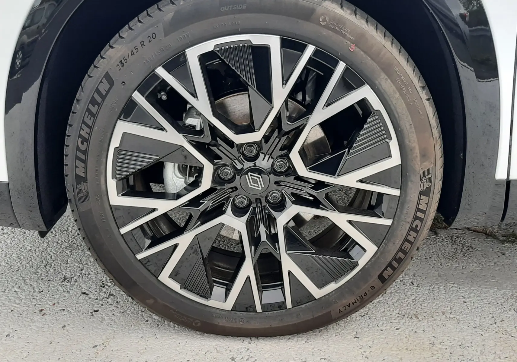 Gros plan sur la jante alliage 20'' noire et argentée du Renault Austral blanc nacré, avec pneu Michelin visible.