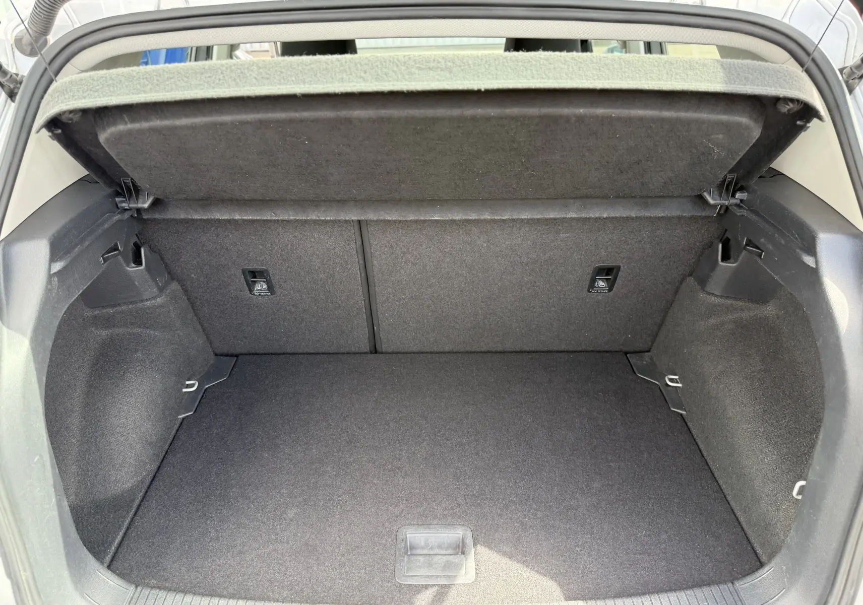 Coffre ouvert en vue arrière d’un Volkswagen T-Cross gris 2019, espace de chargement vide et tapis noir.