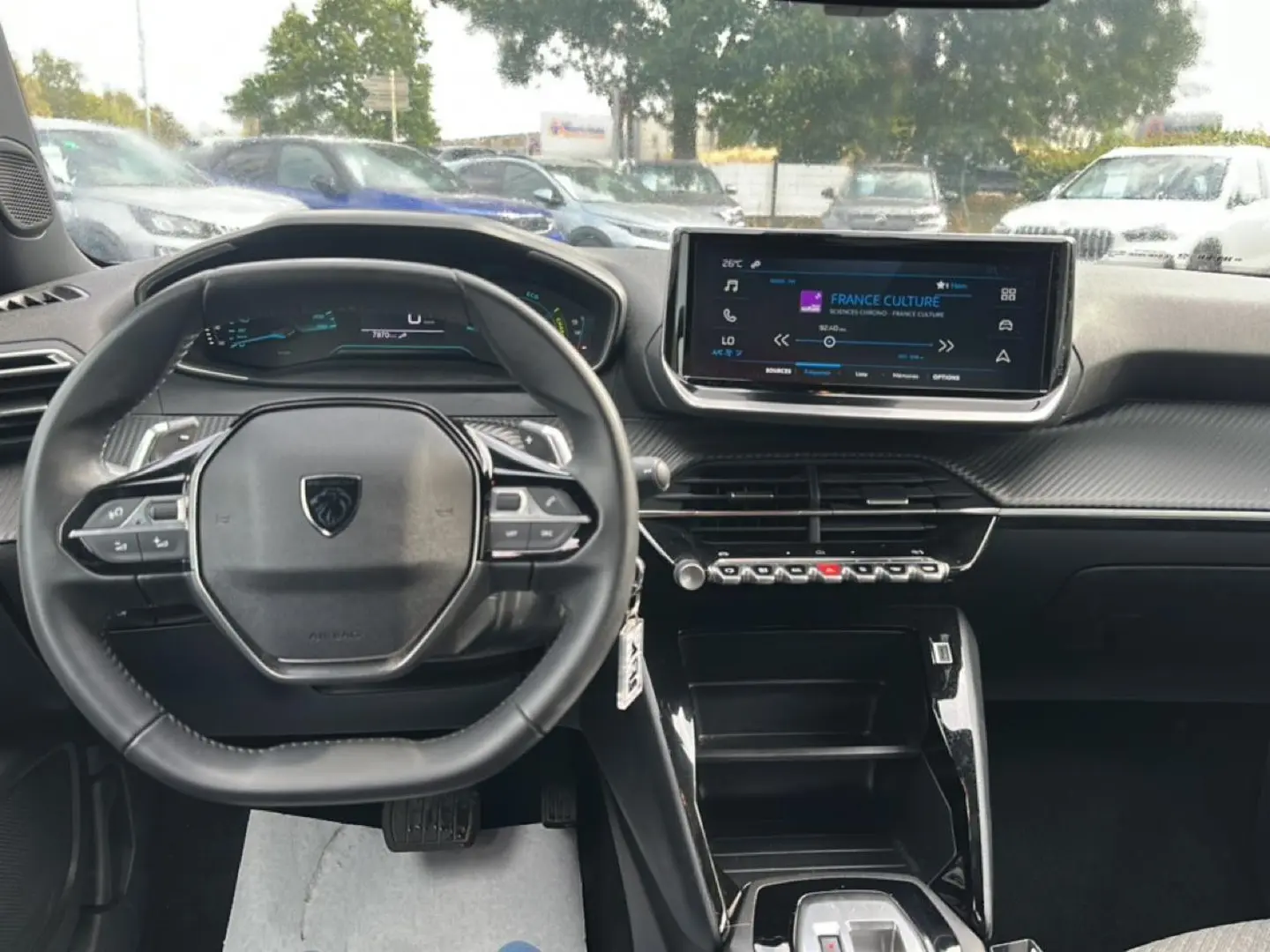 Vue intérieure frontale du tableau de bord du Peugeot 2008 gris, avec volant multifonction et écran tactile central allumé.