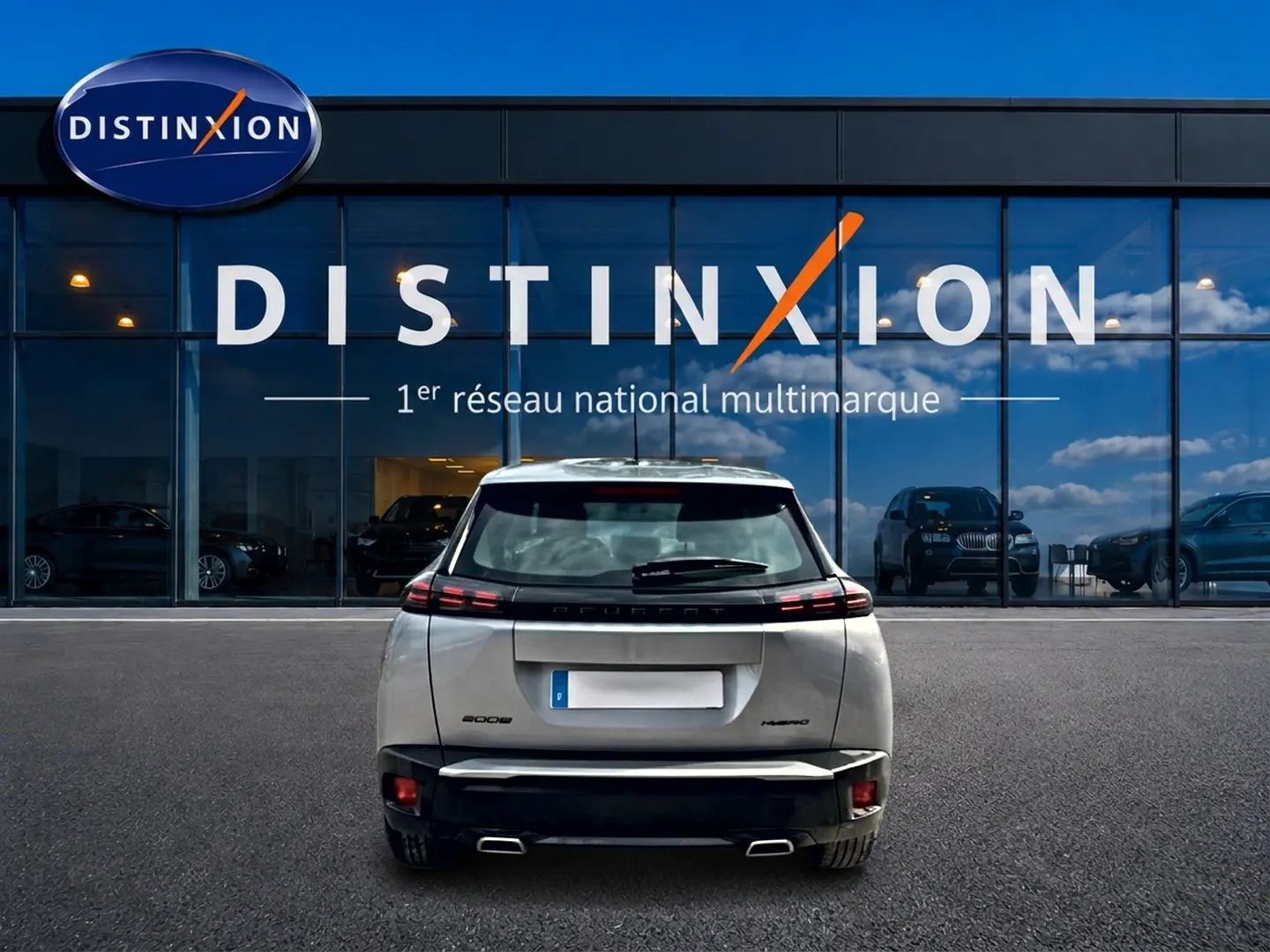 Vue arrière d’un Peugeot 2008 gris 2025 garé devant une vitrine avec logo Distinxion.