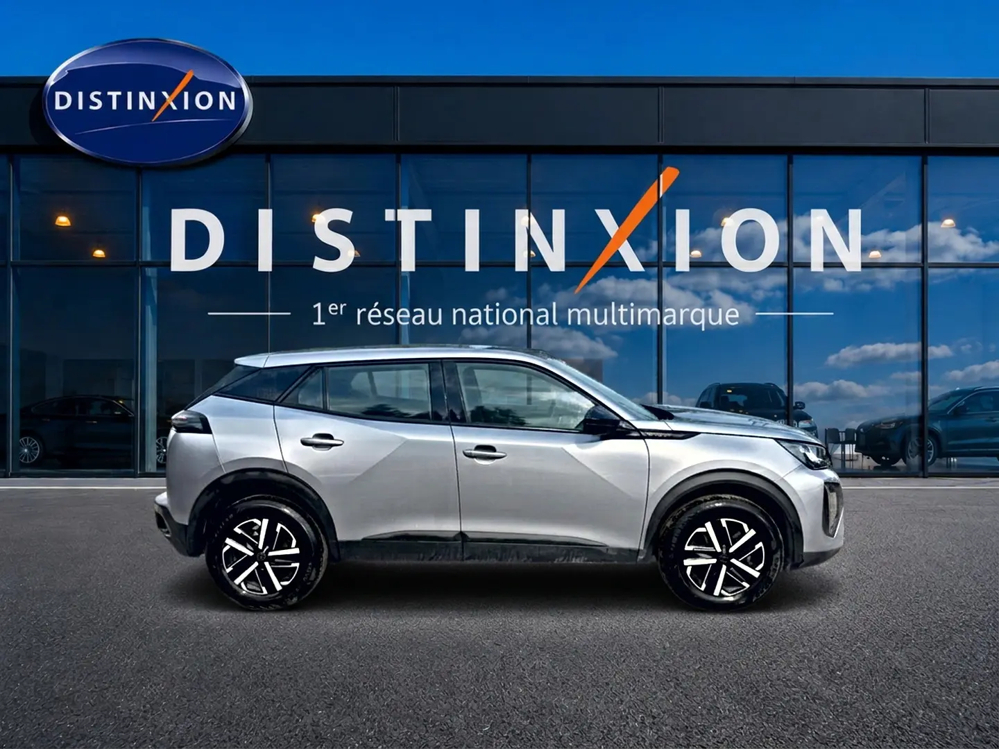 Peugeot 2008 gris en profil droit, avec jantes noires et toit contrasté devant une vitrine Distinxion.