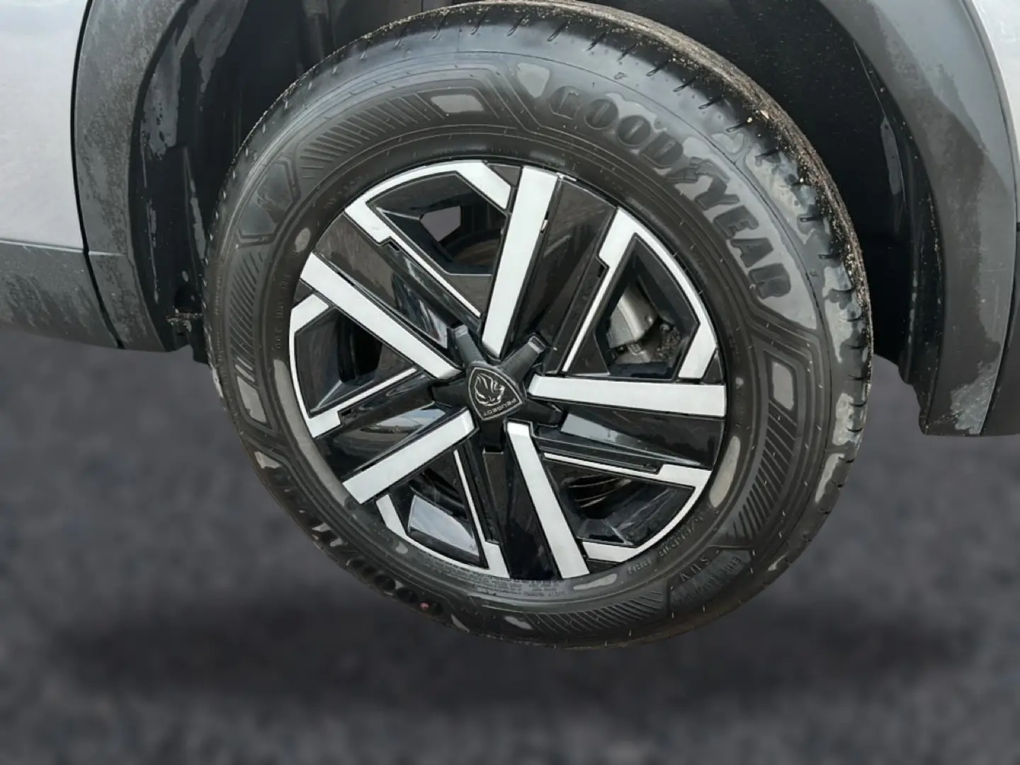 Gros plan sur la roue avant droite du Peugeot 2008 gris, mettant en valeur la jante noire et argentée au design moderne.
