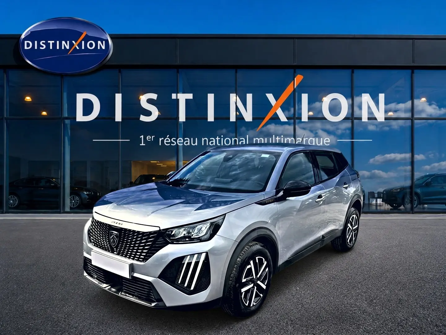 Peugeot 2008 gris en 3/4 avant droit, avec calandre noire et phares LED distinctifs, devant une vitrine Distinxion.