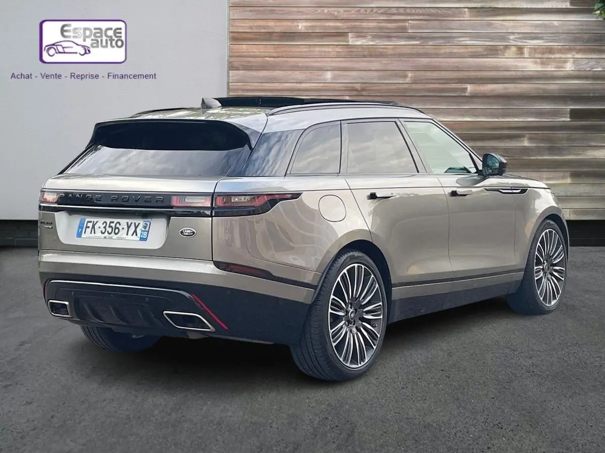 Vue 3/4 arrière droite d'un Range Rover Velar gris 2019 avec toit noir et jantes alliage distinctives.
