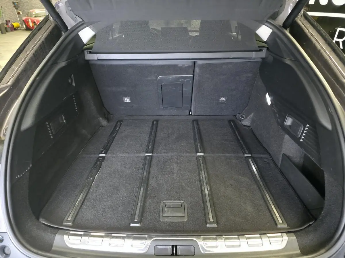 Coffre spacieux ouvert du Citroën C5 X Hybrid gris, avec plancher plat et garniture noire intérieure.