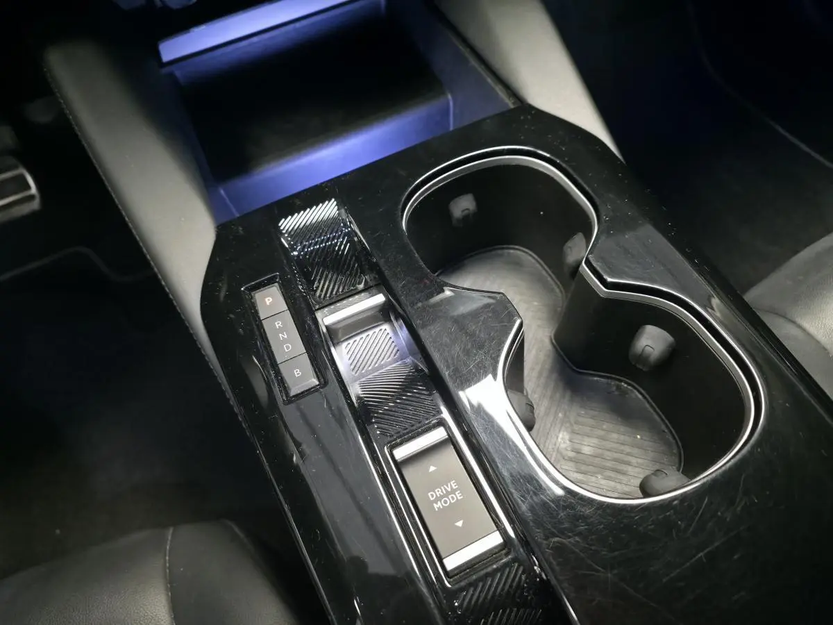 Console centrale noire brillante avec commandes de boîte automatique et porte-gobelets dans une Citroën C5 X Hybrid 2023.