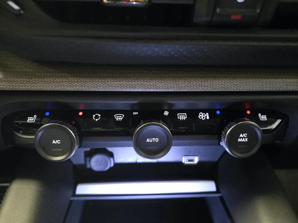 Gros plan sur la console centrale du système de climatisation de la Citroën C5 X hybride rechargeable gris, avec commandes rotatives et voyants lumineux.