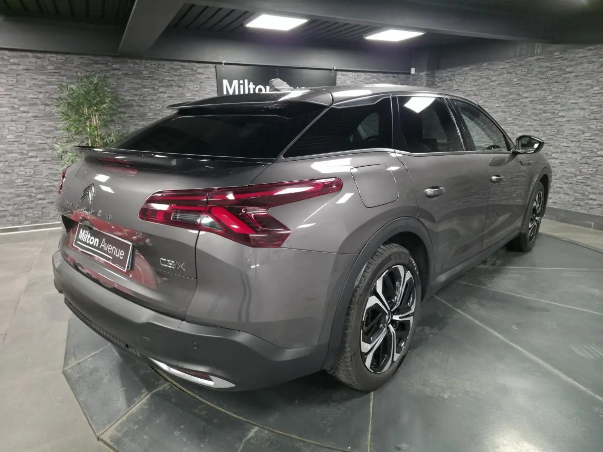 Vue 3/4 arrière droit d'une Citroën C5 X hybride rechargeable gris métallisé avec jantes alliage noires et vitres teintées.