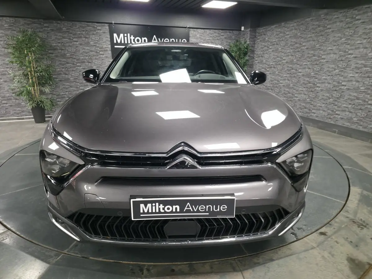 Vue frontale d'une Citroën C5 X hybride rechargeable gris métallisé avec calandre noire et logo chromé visible.