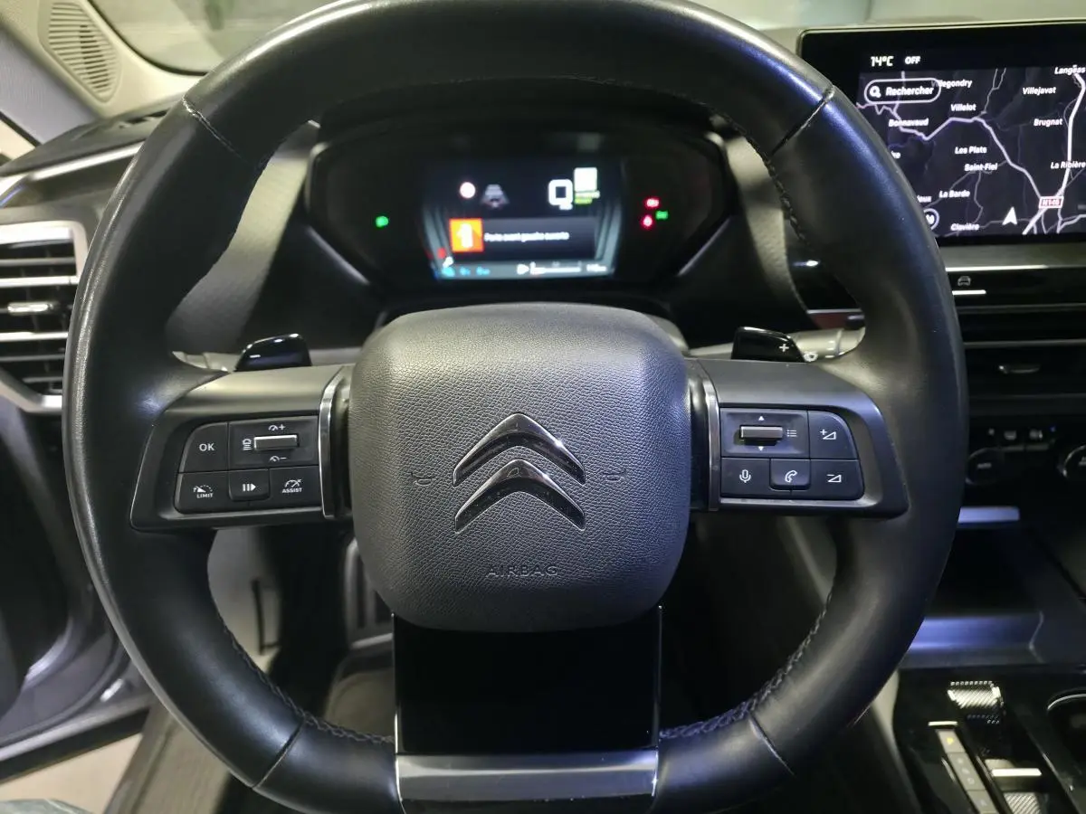 Volant cuir noir de Citroën C5 X Hybrid 2023 avec commandes intégrées et tableau de bord numérique en arrière-plan.
