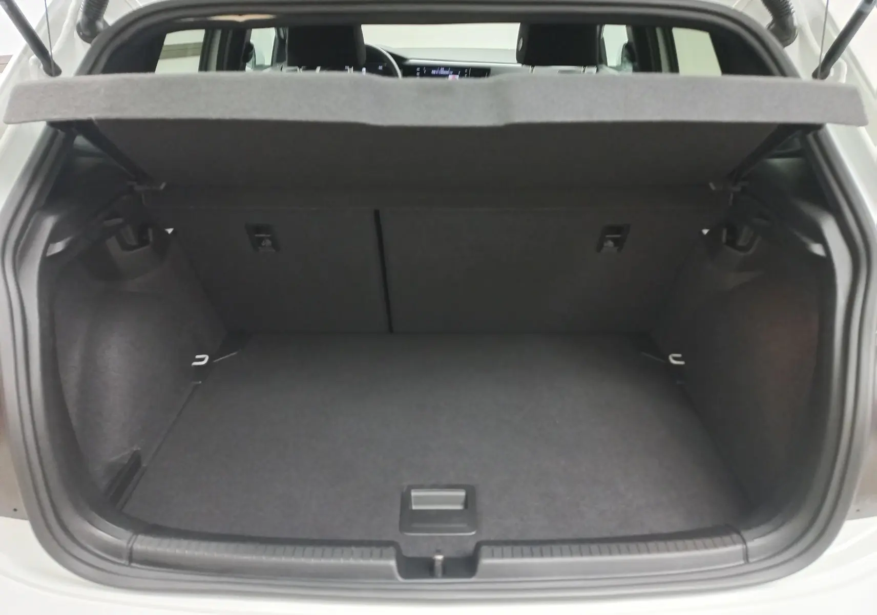 Coffre ouvert de la Volkswagen Polo blanc pur, vue arrière montrant l’espace de chargement et la tablette cache-bagages relevée.