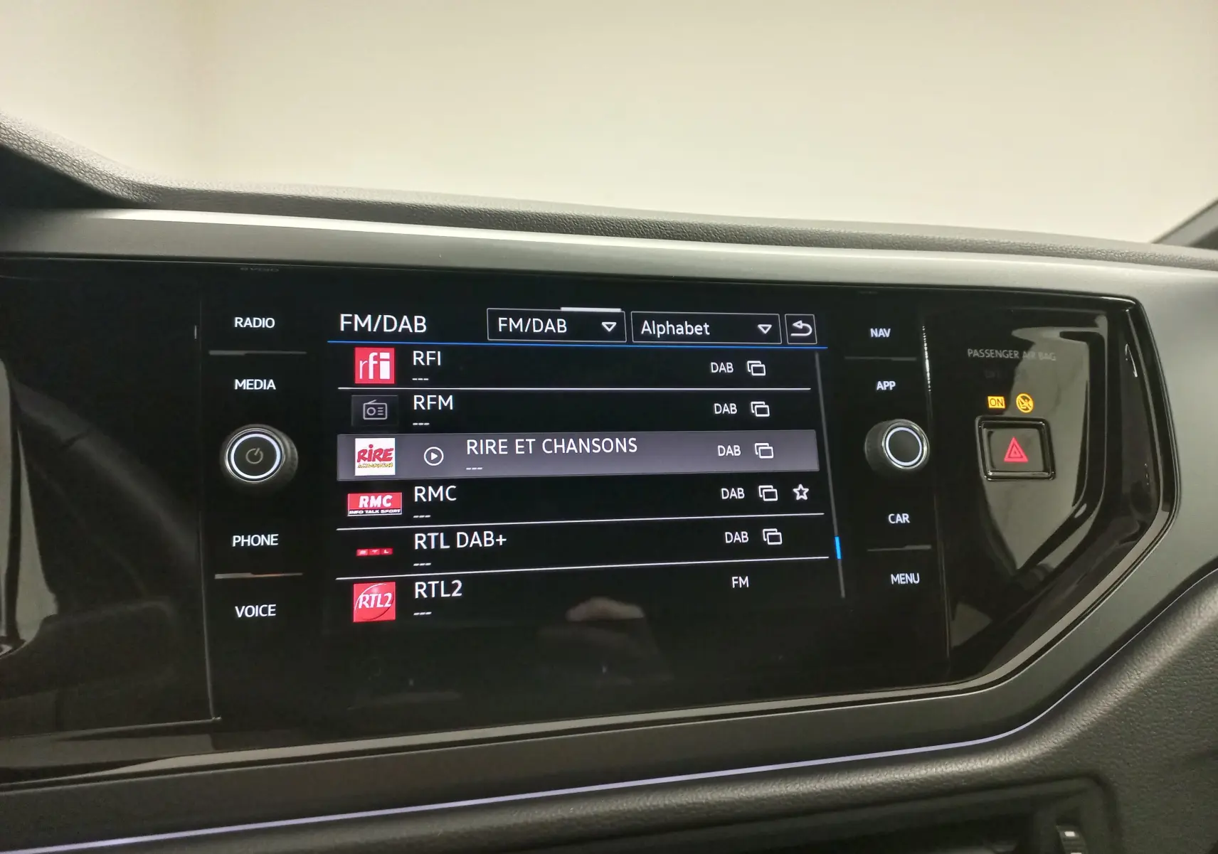 Écran tactile de la radio FM/DAB dans le tableau de bord d'une Volkswagen Polo, affichant plusieurs stations.