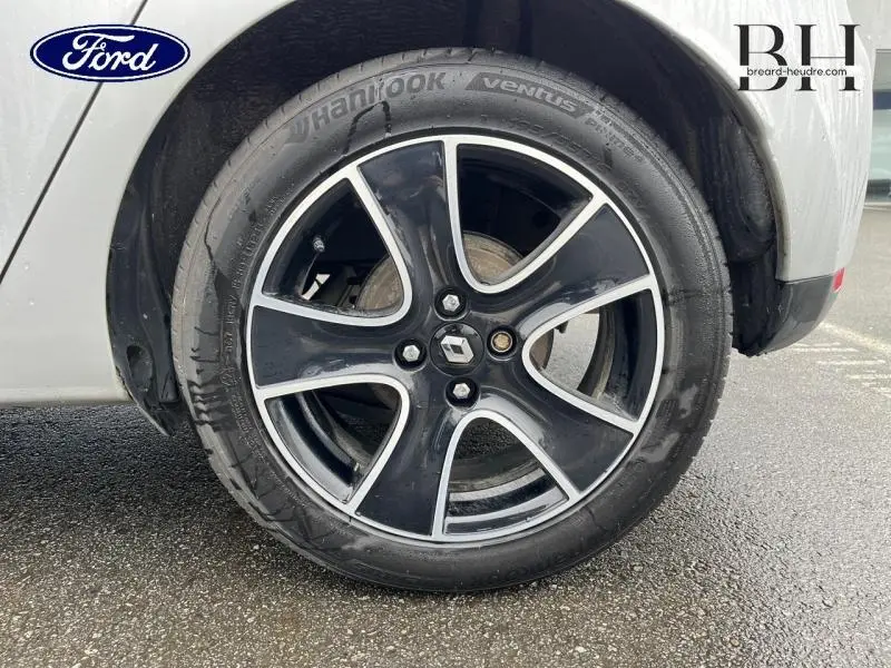 Gros plan sur la roue avant droite avec jante alliage noire et argentée d'une Renault Clio gris platine.