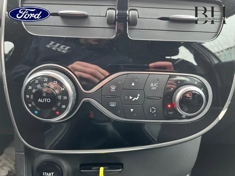 Panneau de commande de climatisation noir brillant d'une Renault Clio gris platine, vue rapprochée centrée.