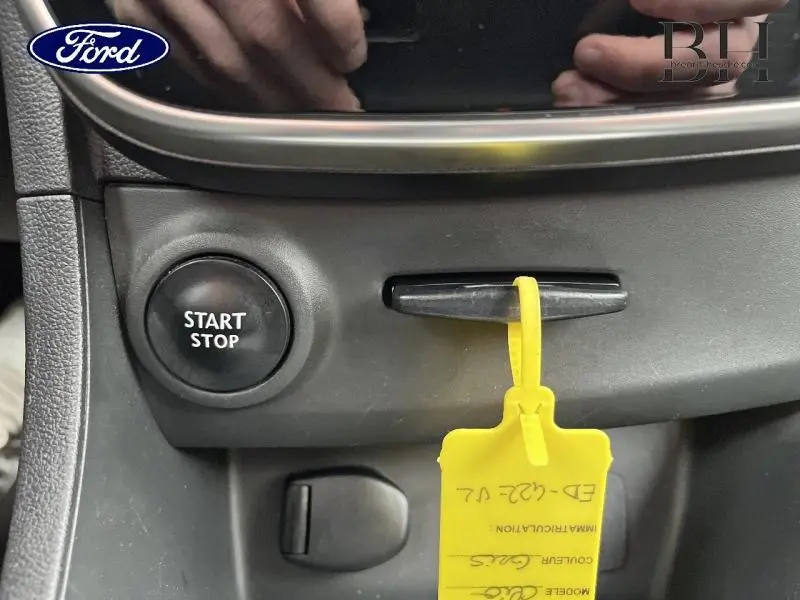 Détail intérieur montrant le bouton Start Stop et un porte-clés jaune dans une Renault Clio gris platine, version 2016.
