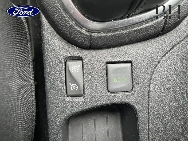 Gros plan sur les boutons de commande Eco et régulateur de vitesse dans l'habitacle d'une Renault Clio gris platine.