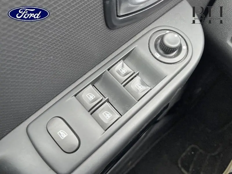 Gros plan sur les commandes de lève-vitres et réglage des rétroviseurs côté conducteur d'une Renault Clio gris platine.