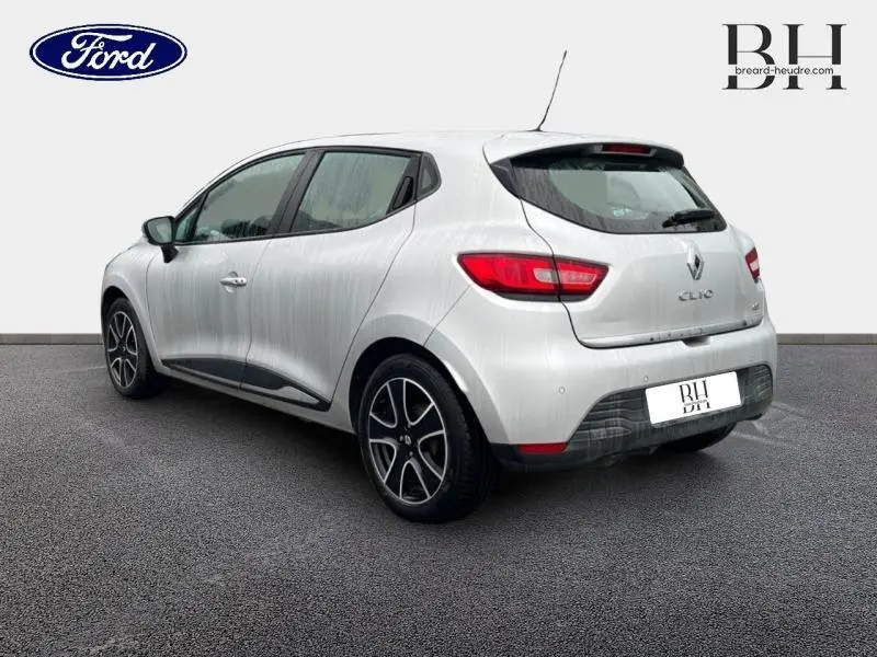 Vue 3/4 arrière droite d'une Renault Clio gris platine avec jantes alu et becquet arrière visible.