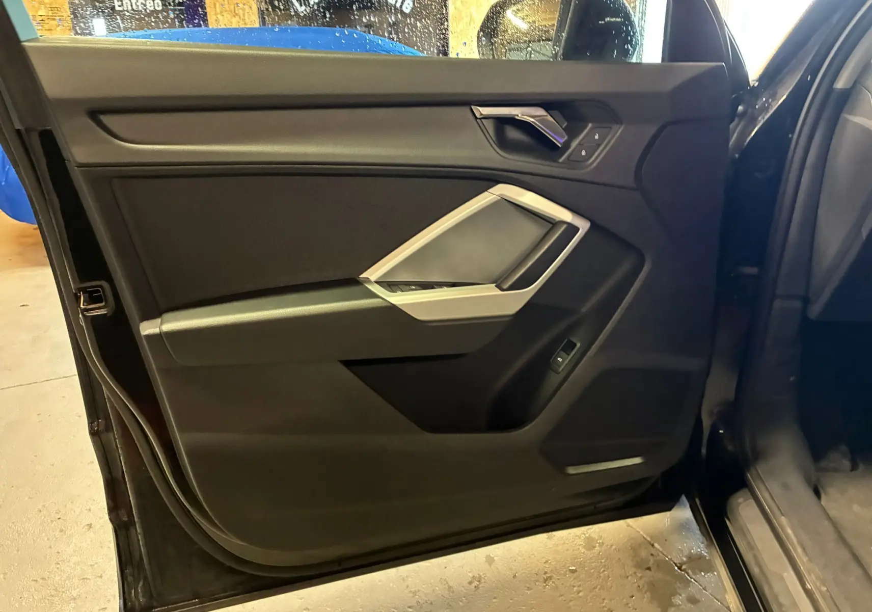 Vue intérieure de la porte avant gauche noire de l'Audi Q3 Sportback 2022 avec détails des commandes et poignée argentée.