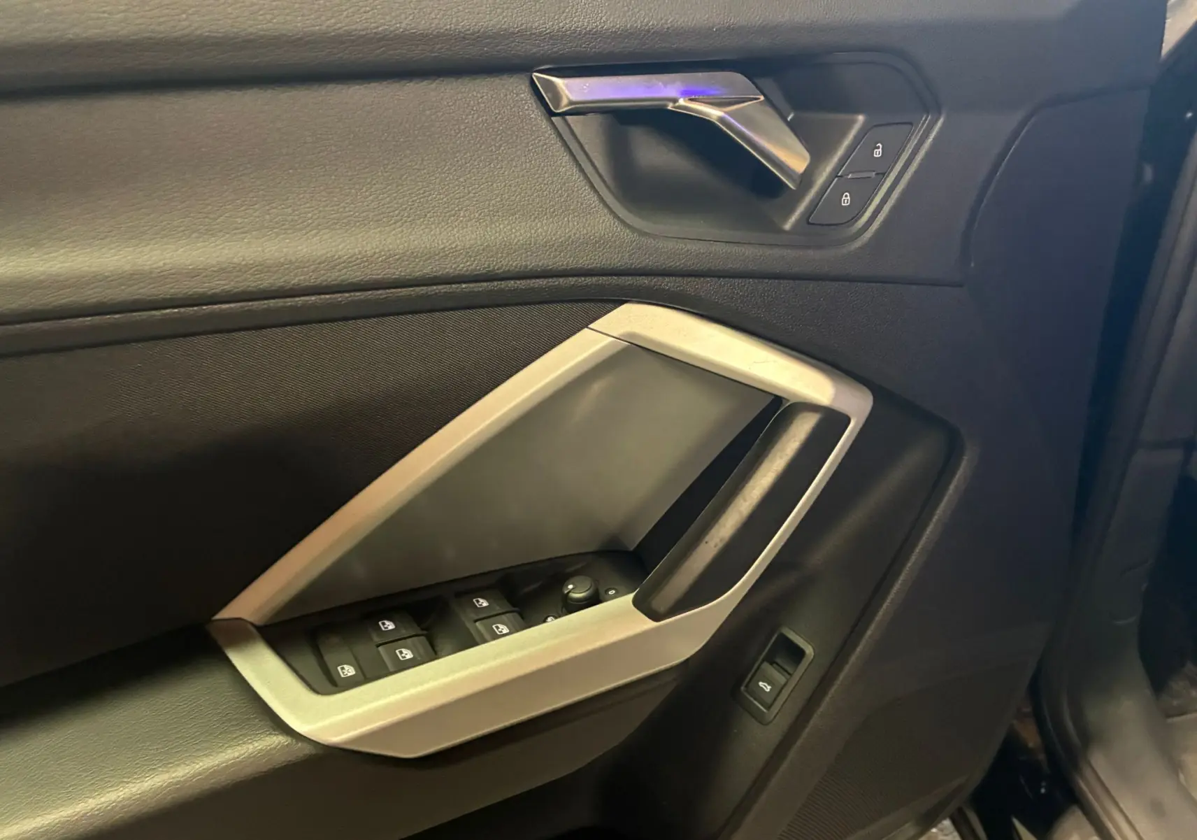 Gros plan sur la porte avant gauche noire de l'Audi Q3 Sportback 2022 avec commandes de vitres et verrouillage.